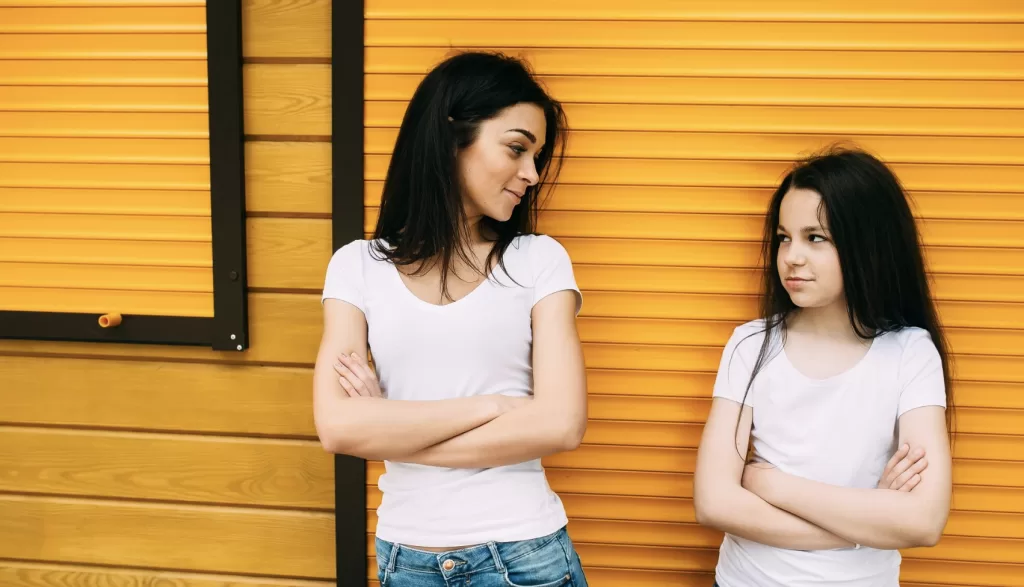 two ladies comparing differences against an orange wall