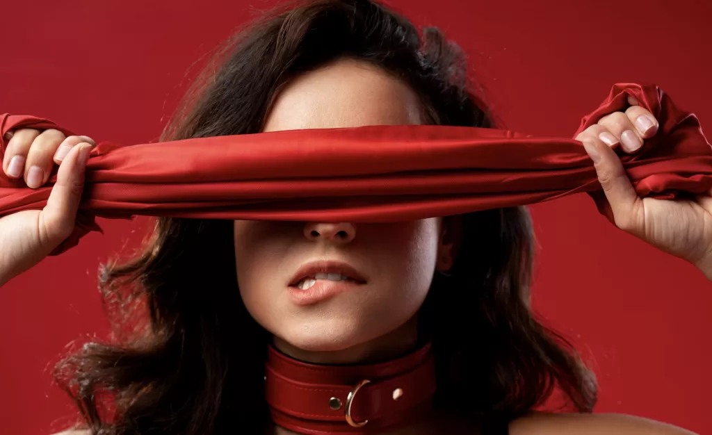 brunette woman covering eyes with red fabric 