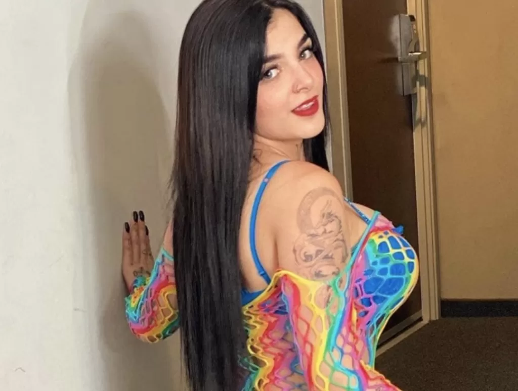 Karely Ruiz Erome selfie in a rainbow outfit smiling behind her shoulder