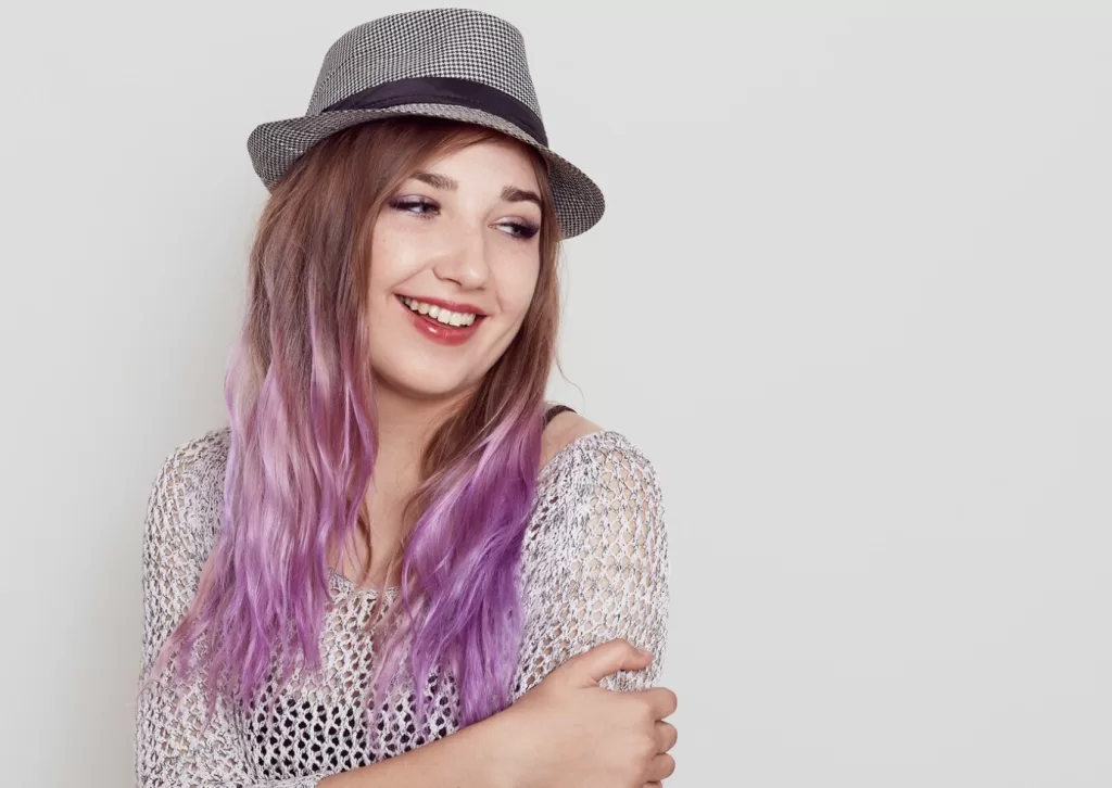 Brazilian lady smiling with top hat and purple hair